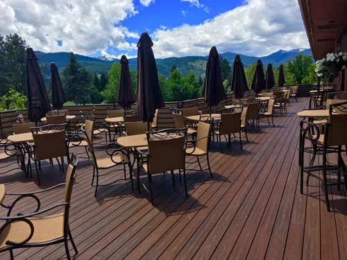 Wooden deck with tables and chairs trees and mountains
